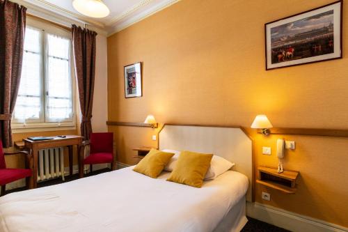 a hotel room with a bed with two yellow pillows at Hôtel des Bains in Aix-les-Bains