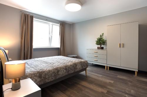 een slaapkamer met een bed, een dressoir en een raam bij Apartament Antracytowy Darłówko in Darlowko