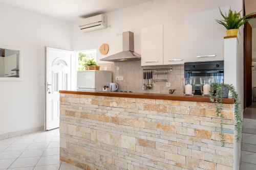 uma cozinha com armários brancos e uma parede de tijolos em Jadrija Bay em Šibenik