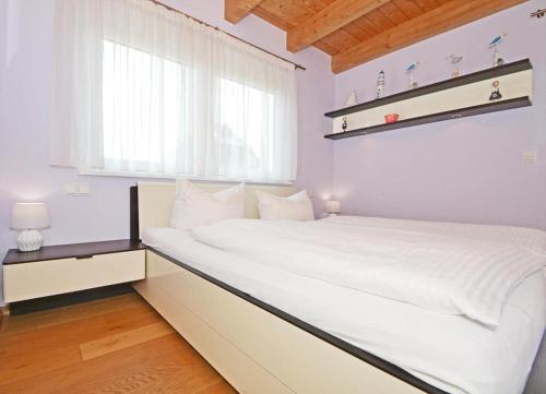 a white bed in a room with a window at Ferienhaus "Das blaue Haus" mit Kamin und Sauna in Ostseebad Koserow