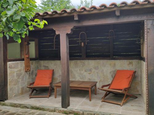 two chairs and a table under a gazebo at Casa el Viñadal in Arguebanes