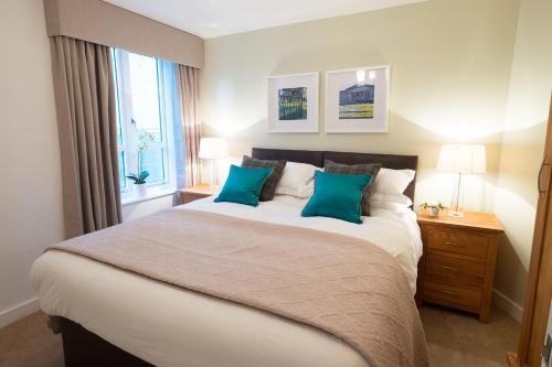 una camera da letto con un grande letto con due cuscini blu di The Malt Kiln Apartment Edinburgh Old Town 3 Bedroom Parking previously McDonald Residence a Edimburgo