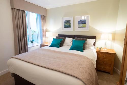 a bedroom with a large bed with two blue pillows at The Malt Kiln Apartment Edinburgh Old Town 3 Bedroom in Edinburgh