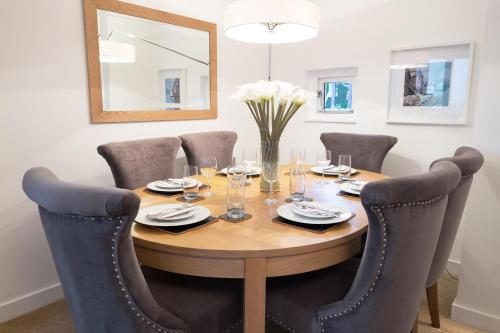 a dining room table with chairs and a wooden table and a mirror at The Malt Kiln Apartment Edinburgh Old Town 3 Bedroom in Edinburgh
