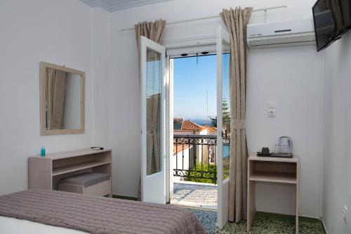 Schlafzimmer mit einem Bett und einer Tür zu einem Balkon in der Unterkunft Argonaftis Spetses in Spetses