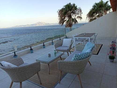 a patio with chairs and a table and the ocean at Punta Carnero Hostal in Algeciras