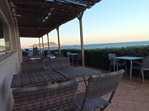 a patio with chairs and tables and a view of the ocean at Punta Carnero Hostal in Algeciras