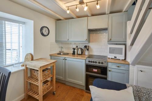 cocina con armarios azules, mesa y microondas en Host & Stay - Amber Cottage en Whitby