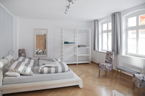 ein weißes Schlafzimmer mit einem Bett und 2 Stühlen in der Unterkunft Appartement Schloßstraße in Ballenstedt