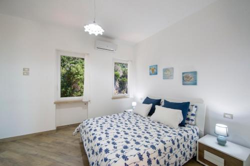 a white bedroom with a bed and two windows at Casa Licia in Positano