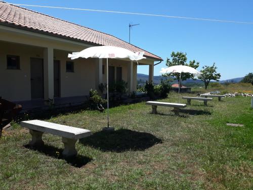 a group of benches with umbrellas in the grass at Pensão Repouso do Peregrino in Paredes de Coura