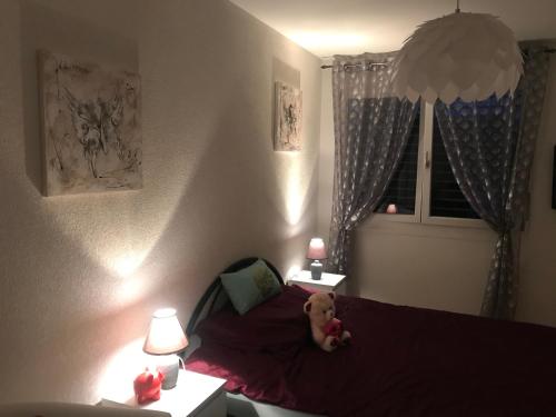 a teddy bear sitting on a bed in a bedroom at Chambre d hôtes Le Petit Bonheur in Colombier