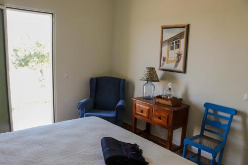 a bedroom with two chairs and a bed and a desk at Quinta da Soneca in Alandroal