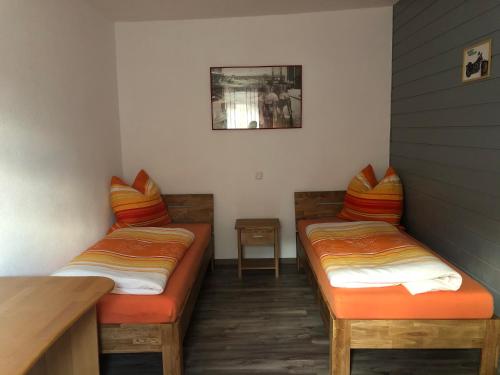 two beds with orange cushions in a room at Gasthaus Riebel in Kirchendemenreuth