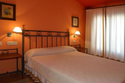a bedroom with a bed and two lamps and a window at Hotel y apartamentos La Casa Rural in Chinchón