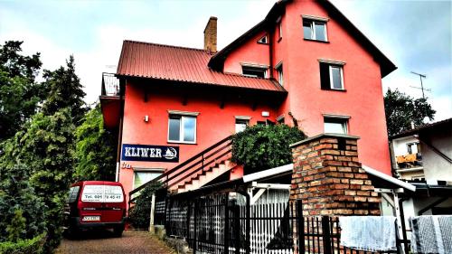 una casa roja con un autobús rojo estacionado frente a ella en KLIWER MIĘDZYZDROJE en Międzyzdroje