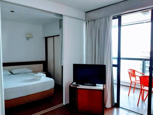 a bedroom with a bed and a television and a balcony at Hotel Flat Atlântico in Fortaleza