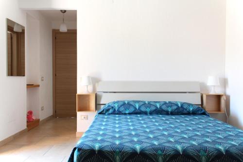 a bedroom with a large bed with a blue comforter at Acquachiara Rooms in Villasimius