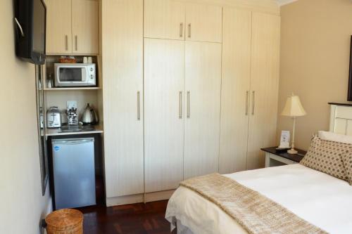 a bedroom with white cabinets and a bed and a microwave at A&A Guesthouse in Port Elizabeth