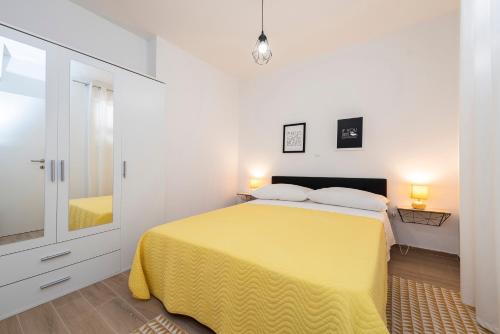 ein weißes Schlafzimmer mit einem gelben Bett und einem Spiegel in der Unterkunft Matej in Bibinje