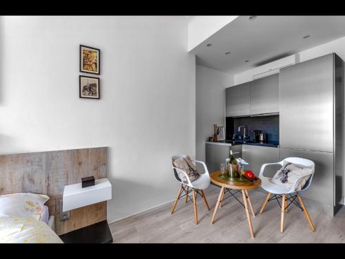 Cet appartement comprend une chambre avec deux chaises et une table ainsi qu'une cuisine. dans l'établissement La Croisette - Superbe studio au mythique Palais Miramar, à Cannes