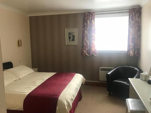 Pokój hotelowy z łóżkiem, krzesłem i oknem w obiekcie Empire Travel Lodge w mieście Lochgilphead