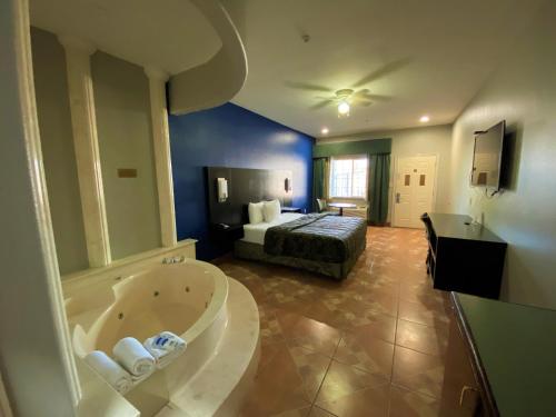 1 dormitorio con 1 cama y baño con bañera. en Texas Inn Alamo, en Alamo