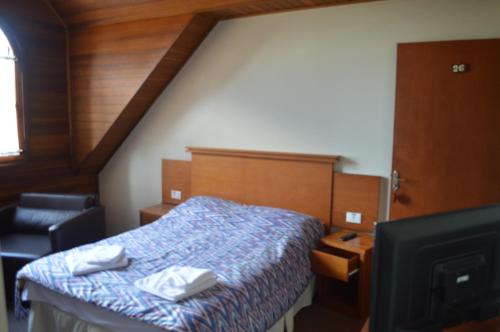 a small bedroom with a bed and a tv at Pousada Campos do Jordão in Campos do Jordão