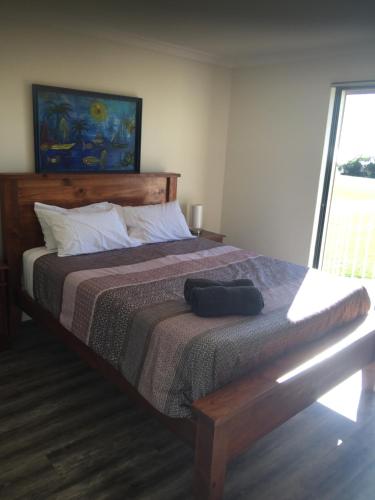 a bedroom with a large bed with a wooden headboard at Long Beach Retreat Townhouse in Warnbro