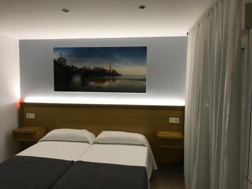 a bedroom with a bed and a painting on the wall at Hostal Libertad in Gijón
