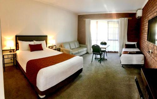 Cette chambre comprend un grand lit et un canapé. dans l'établissement Ararat Colonial Lodge Motel, à Ararat