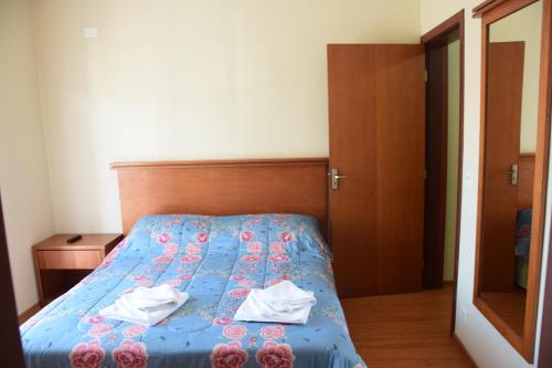 a bedroom with a blue bed with towels on it at Pousada Campos do Jordão in Campos do Jordão