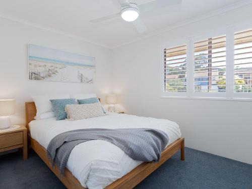 a bedroom with a bed with white walls and windows at Pelican Sands 3 stunning waterfront unit with magical water views and air conditioning in Soldiers Point