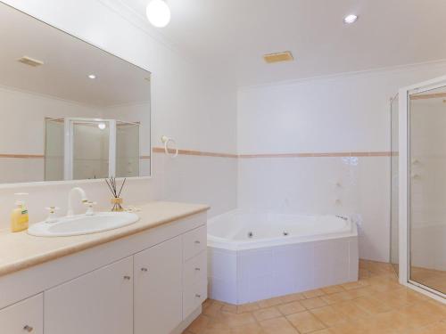 a white bathroom with a sink and a bath tub at Peninsula Waters 2 three bedroom unit with spacious private courtyard and WI-FI in Soldiers Point