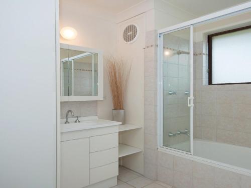 a white bathroom with a shower and a sink at Promenade 11, 8 Intrepid Close - air conditioned unit with beautiful water views in Shoal Bay