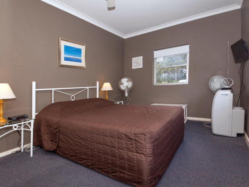 a bedroom with a bed and a desk and a television at Quarterdeck 5 panoramic water views and close to town in Nelson Bay