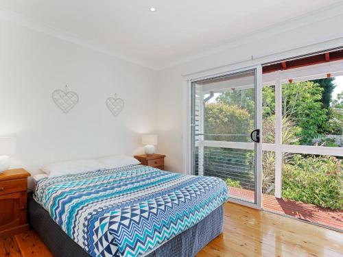 une chambre avec un lit et une grande fenêtre dans l'établissement Rubys Retreat, 44 Achilles Street - pet friendly, aircon, wifi & boat parking, à Shoal Bay