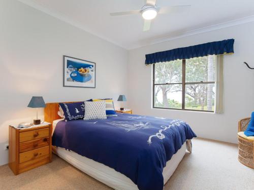 ein Schlafzimmer mit einem blauen Bett und einem Fenster in der Unterkunft Sailfish, 4,46 Magnus Street- Unit with water views and close to town in Nelson Bay