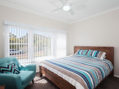 um quarto com uma cama, uma cadeira e uma janela em Sandy Shoal Shoal Bay Beach Cottage with aircon em Shoal Bay