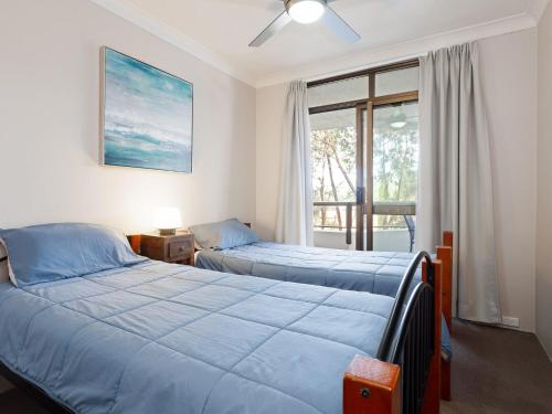 two beds in a room with a window at The Commodore, 14, 9-11 Donald Street- Unit in the heart of town with views & free wi-fi in Nelson Bay