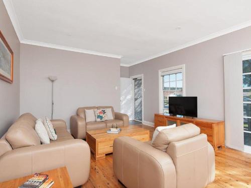 a living room with two couches and a tv at The Croft Cosy Beach House with Aircon and only 270m to the Beach in Fingal Bay