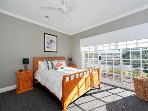 a bedroom with a bed and a large window at The Croft Cosy Beach House with Aircon and only 270m to the Beach in Fingal Bay