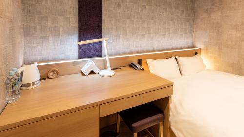a bedroom with a desk with a bed and a lamp at Galois Hotel Shinokubo in Tokyo