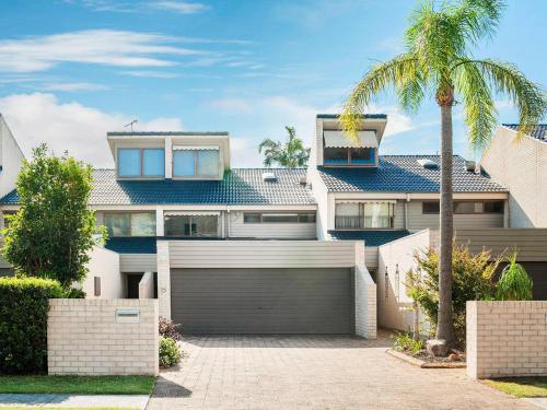 a house with a garage and a palm tree at The Moorings 15 stunning with water views and pool in Soldiers Point