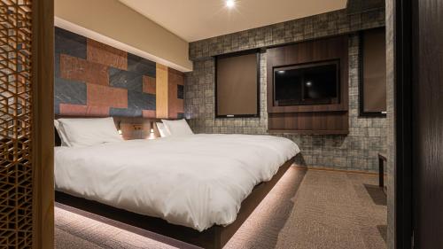 a bedroom with a large bed and a flat screen tv at Galois Hotel Shinokubo in Tokyo
