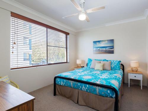 a bedroom with a bed with blue sheets and a window at The Poplars, 6,36 Magnus Street - Unit with fabulous views and a complex pool in Nelson Bay