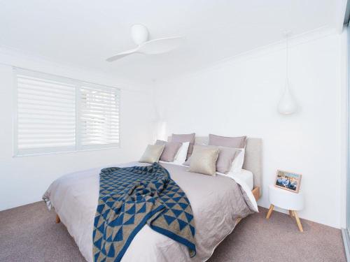 a white bedroom with a large bed and a window at The Poplars, 24,36 Magnus Street - Unit with views, air con and wifi in a complex with a pool in Nelson Bay