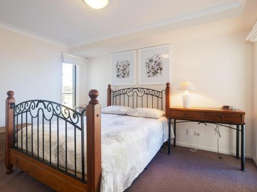 1 dormitorio con cama de madera y escritorio de madera en The Whale Watcher waterfront unit with stunning views level access en Anna Bay