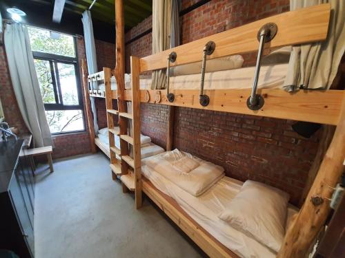 a room with three bunk beds in a brick wall at 缽割貓點點 青旅 DianDian hostel in Puli