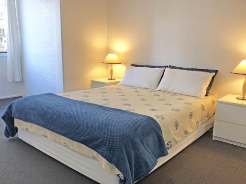 1 dormitorio con 1 cama con manta azul en Villa Ellisa 2 Beautiful water views and directly across to Little Beach, en Nelson Bay